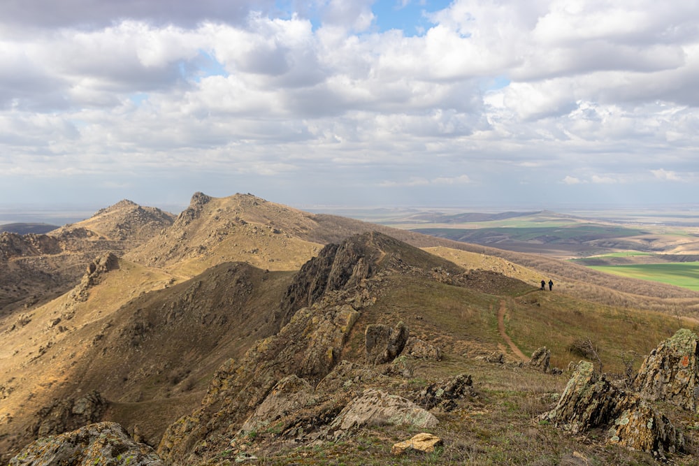 a man standing on top of a mountain next to a lush green field