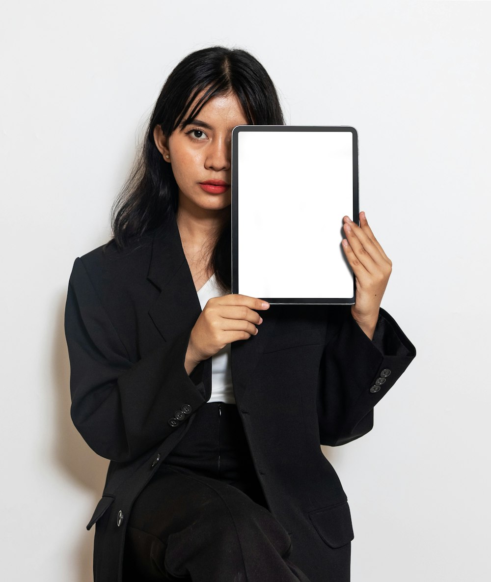 a woman in a suit holding up a tablet
