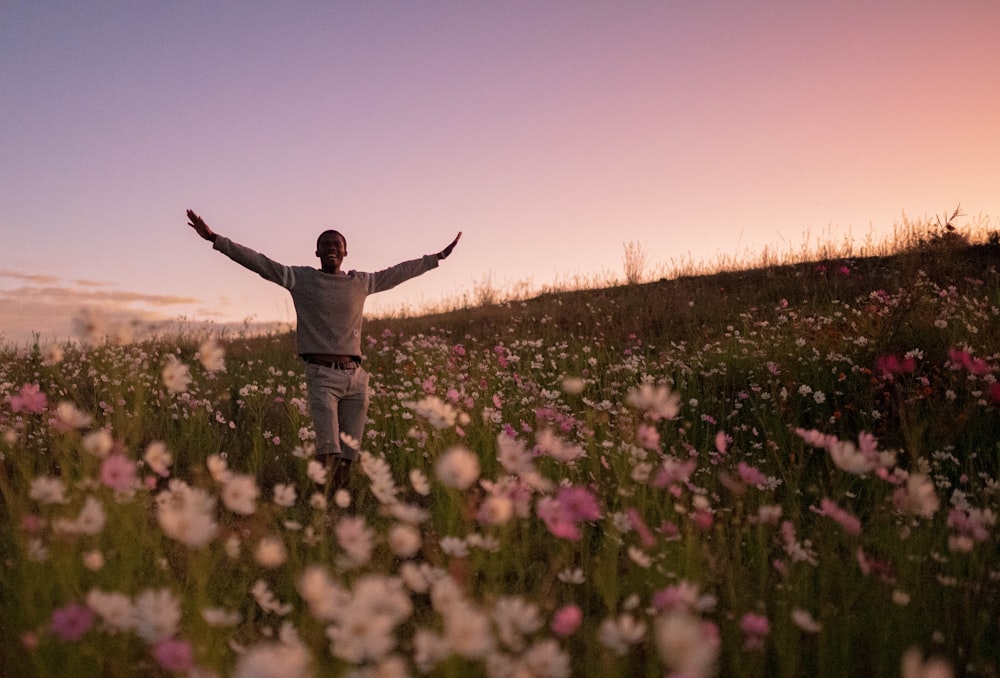 a man standing in a field of flowers with his arms outstretched