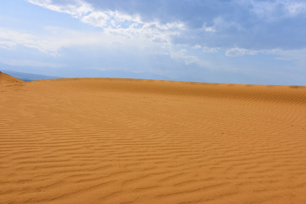 a large sand dune with a blue sky in the background