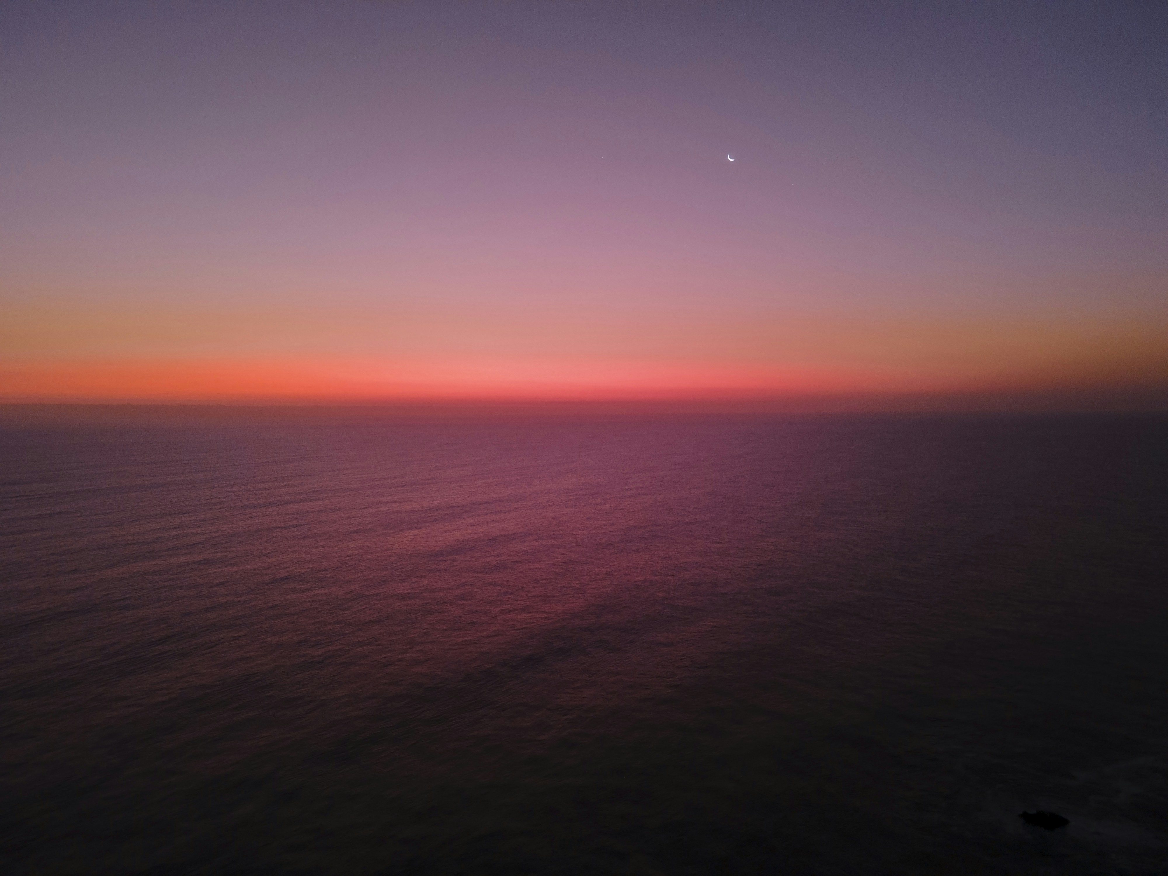 the sun is setting over the ocean as seen from an airplane