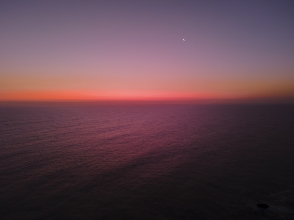 the sun is setting over the ocean as seen from an airplane
