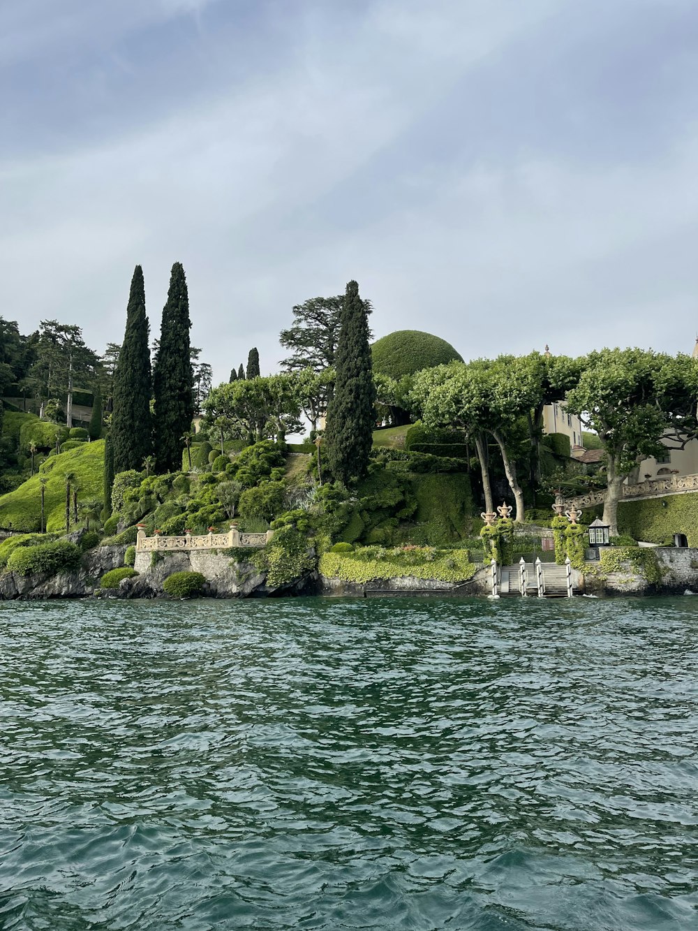 a large body of water next to a lush green hillside