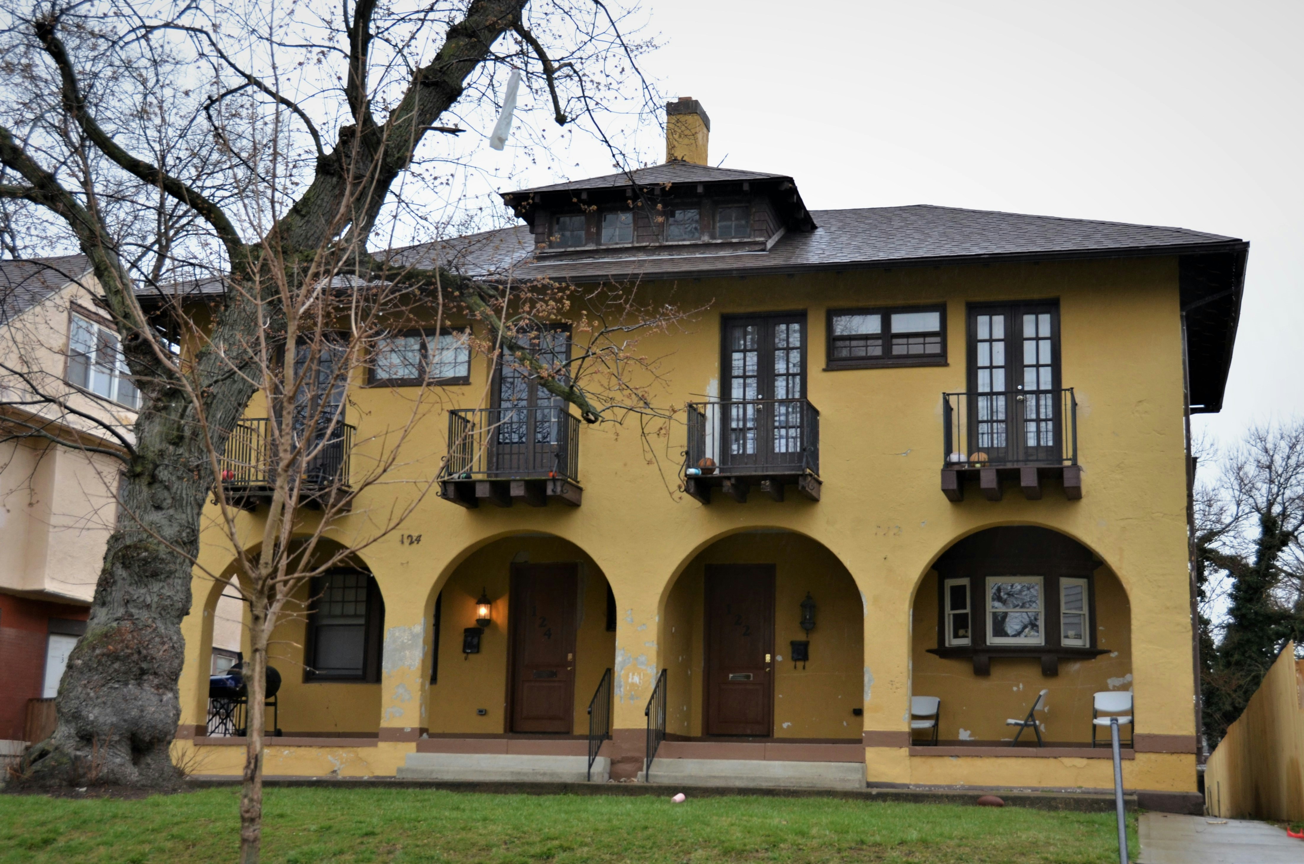 a yellow house with a tree in front of it