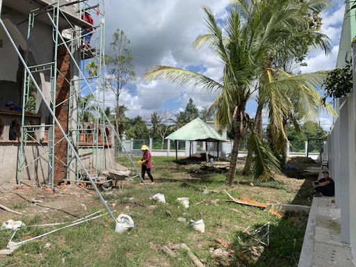 Architect reviewing building plans on a construction site with workers and scaffolding in the background.