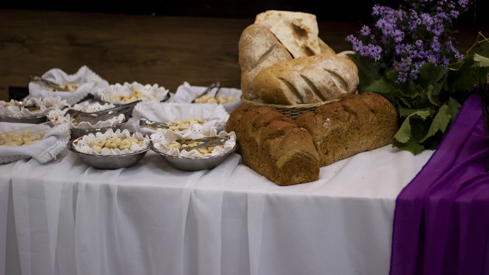 a table topped with a loaf of bread and bowls of food