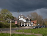 A winding country lane lined with ancient trees leading to a quaint village pub.