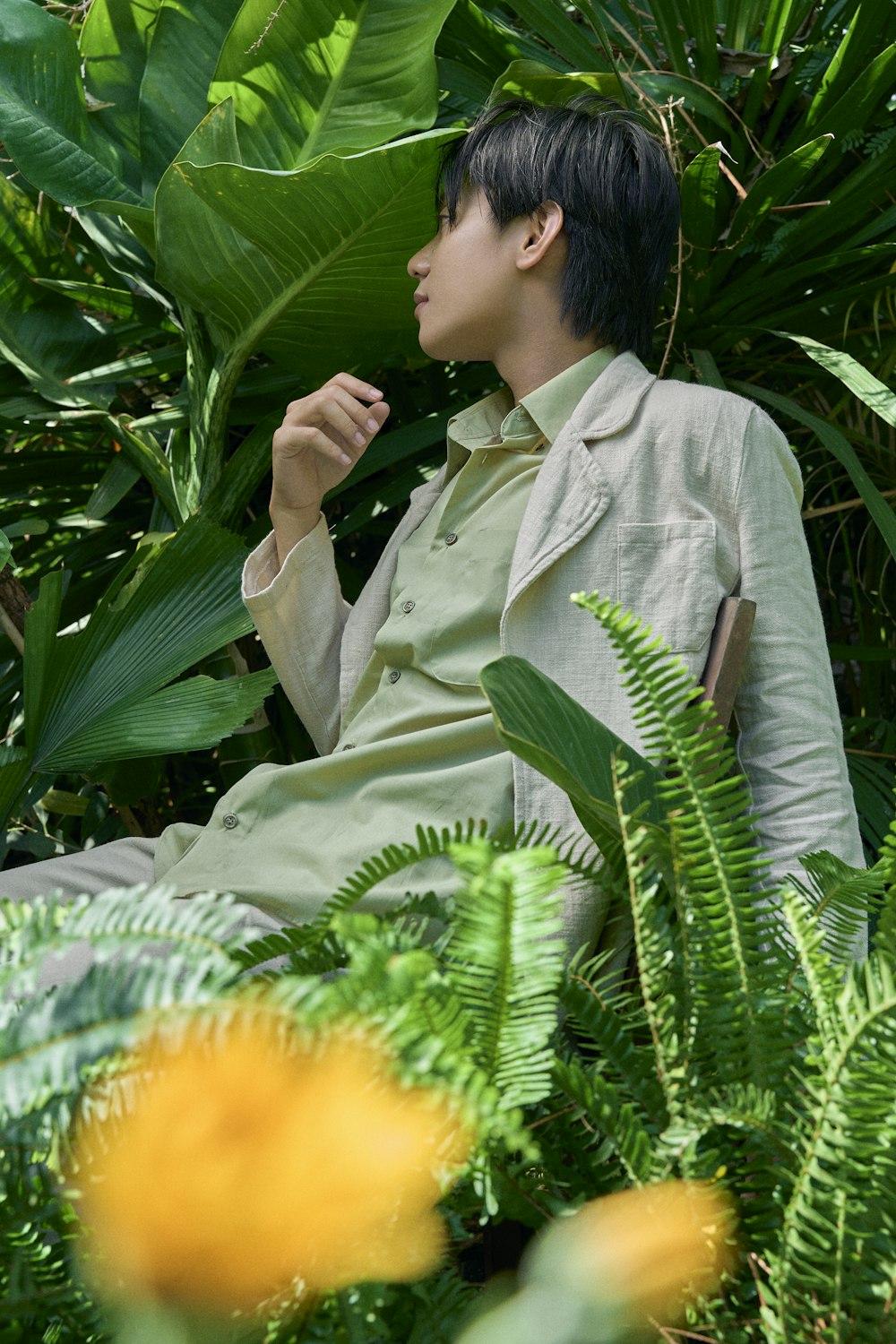 a man sitting on a bench surrounded by plants