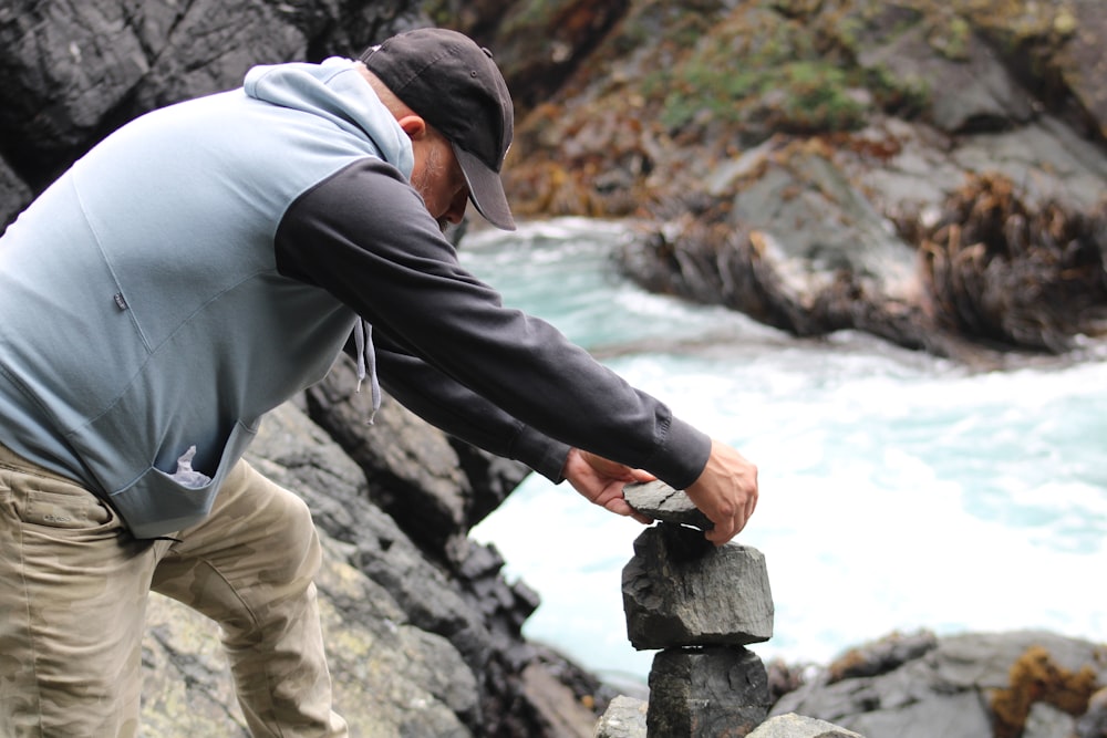 a man balancing rocks on a rock by a river