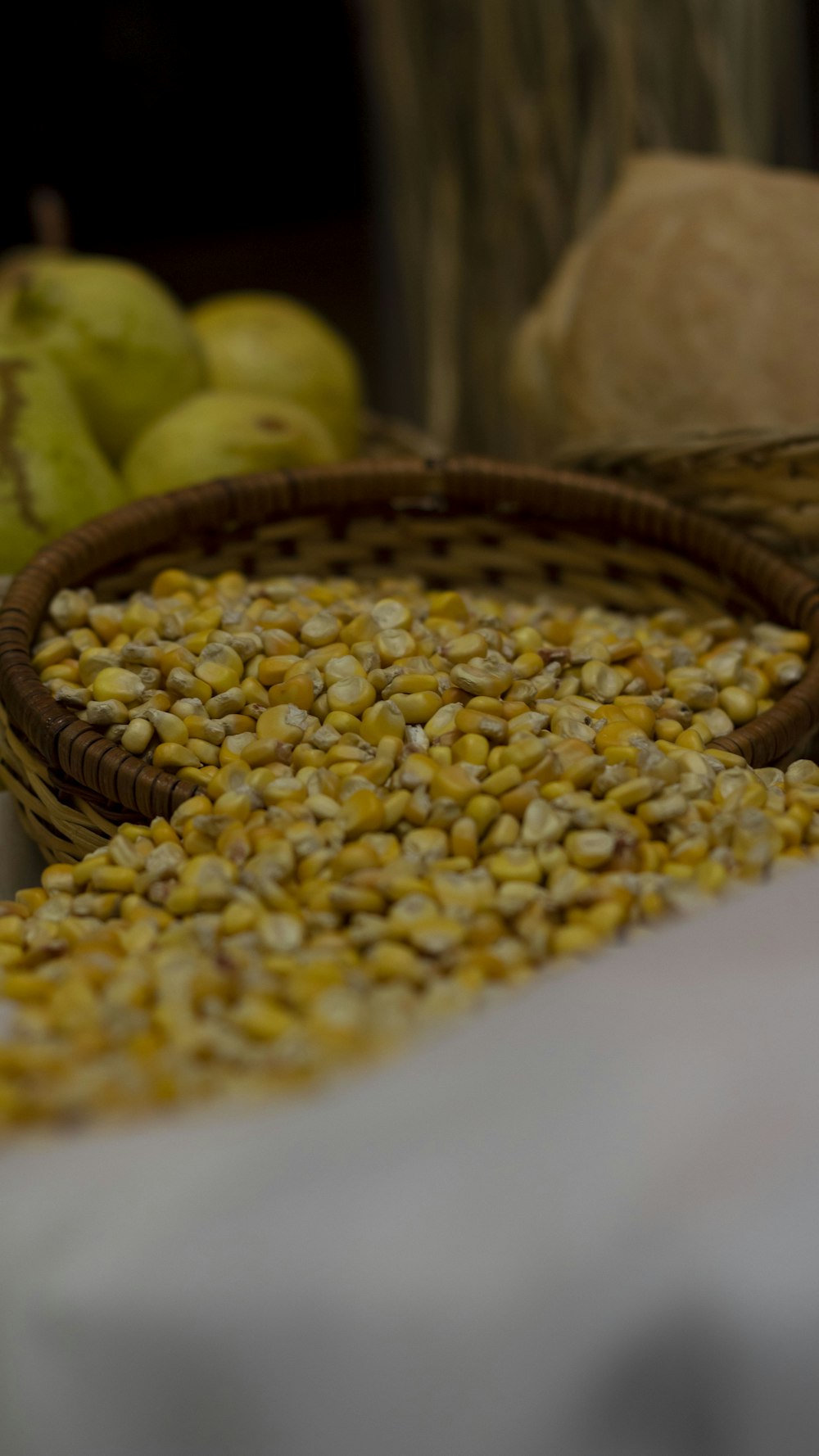 a basket filled with corn next to a pile of apples