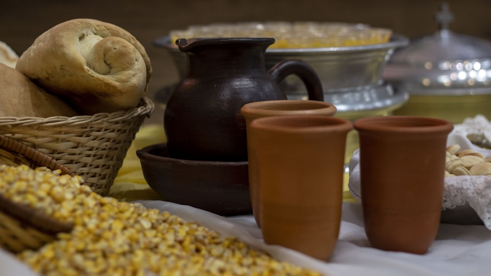 a table topped with a basket of corn next to two cups