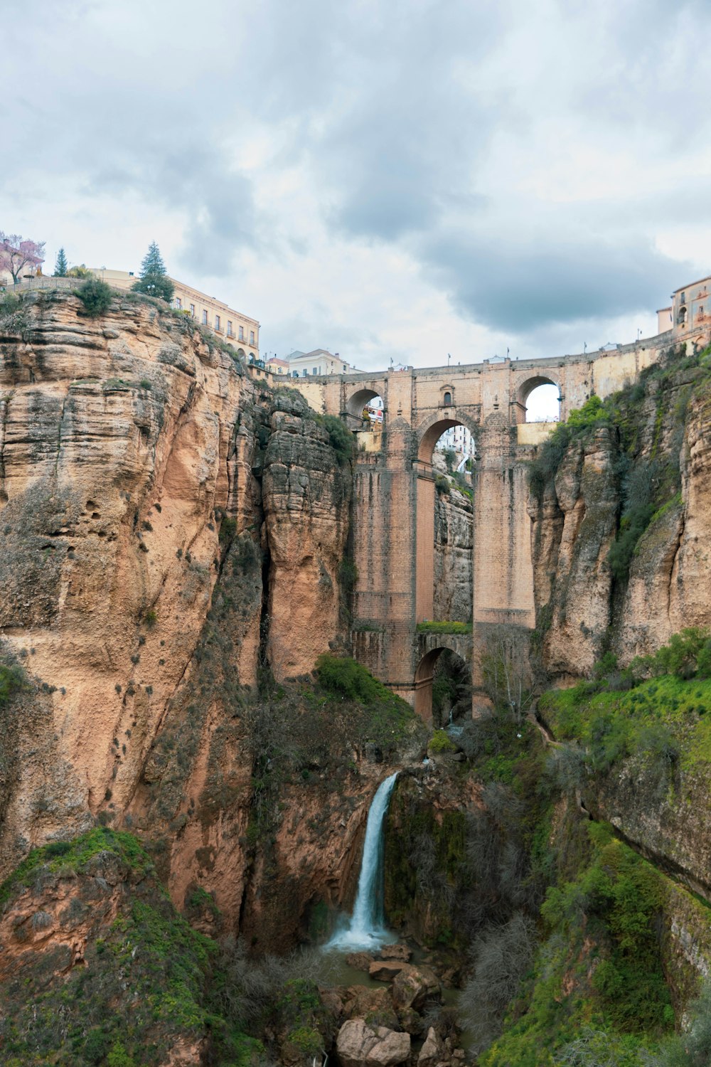 a waterfall in a canyon with a bridge in the background