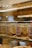 Several glass jars filled with layered dessert are arranged on a glass shelf. The jars have a label with the word 'takava' and a logo. The dessert appears layered with creamy and crumbly textures.