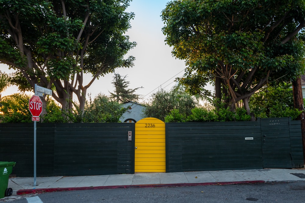 a black fence with a yellow gate and a stop sign