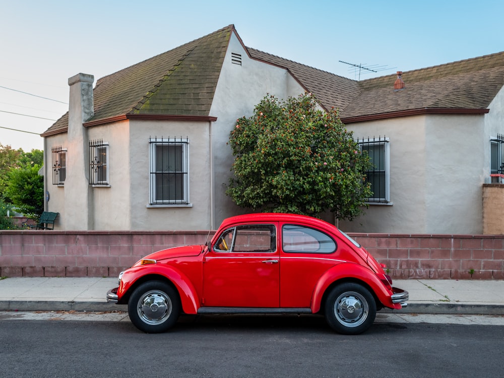 Un coche rojo aparcado frente a una casa