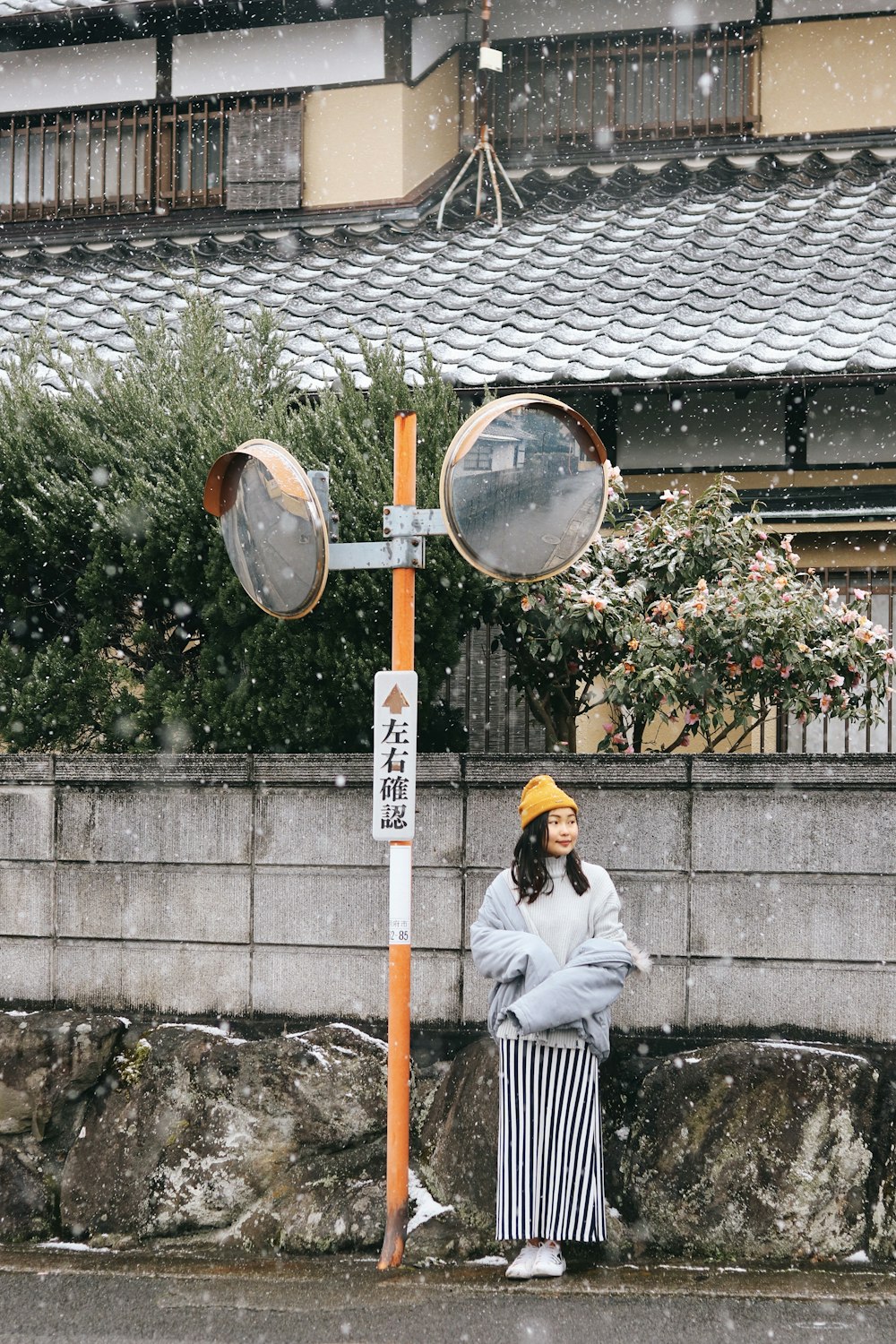 a woman standing next to a street light in the snow