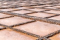 A series of rectangular salt pans are arranged in a geometric pattern. The pans are bordered by small, dark stones, creating a grid-like appearance. The surfaces of the pans have a light brown and white coloring, indicative of the salt crystallization process.