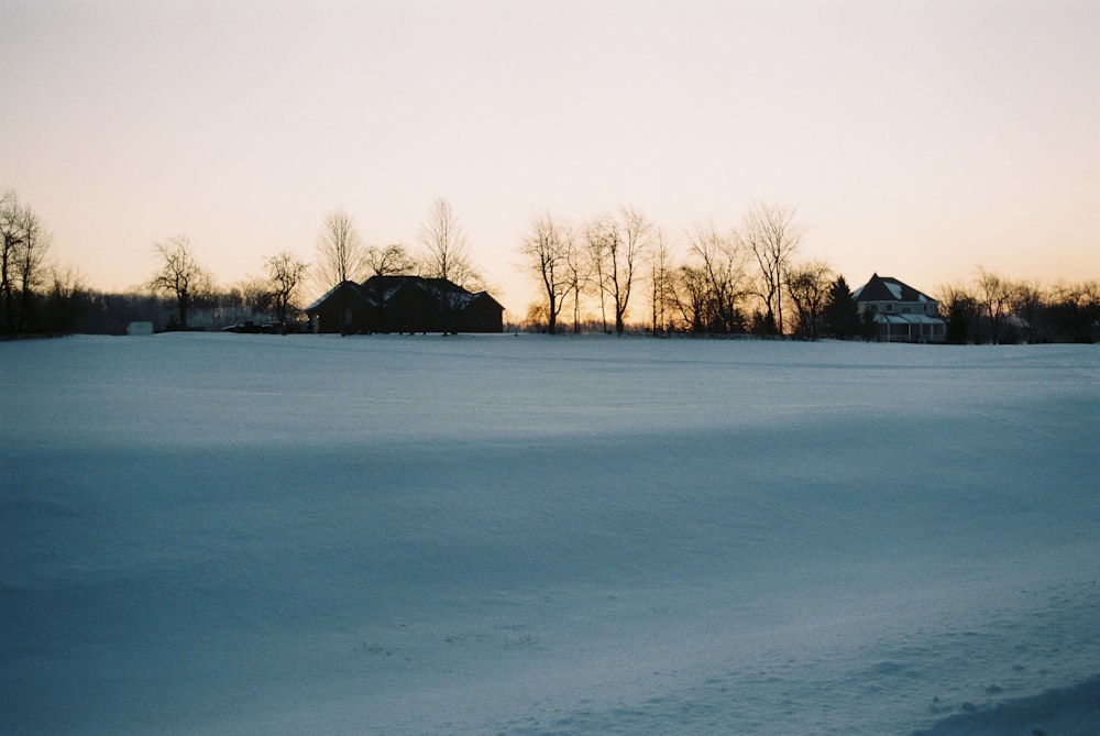 a snow covered field with houses in the distance