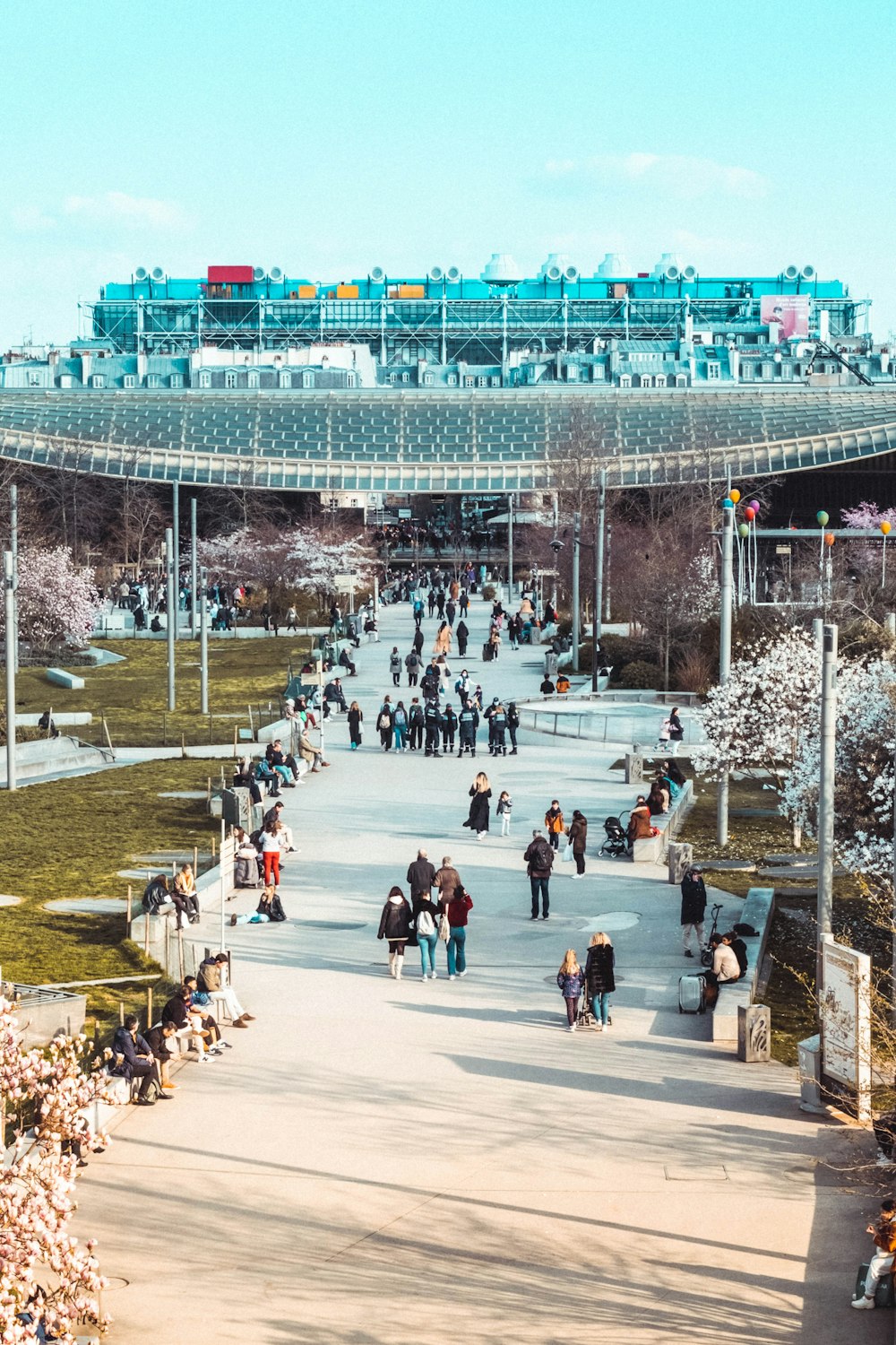 a group of people walking down a walkway in a park
