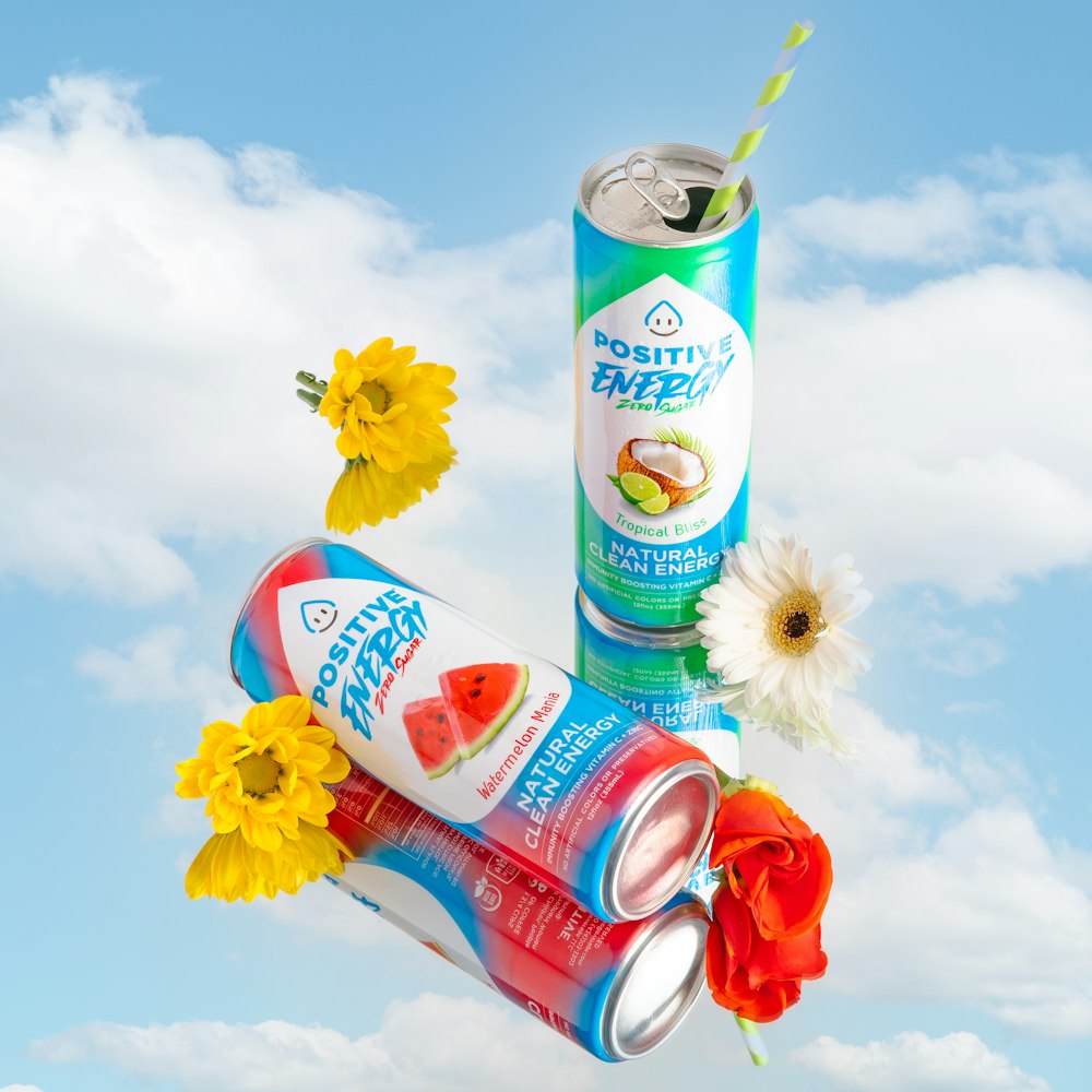 a can of soda and a can of water with a flower