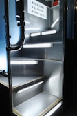 Metallic stairs with illuminated railings and a safety notice in Korean text are visible. The lighting provides a futuristic atmosphere.