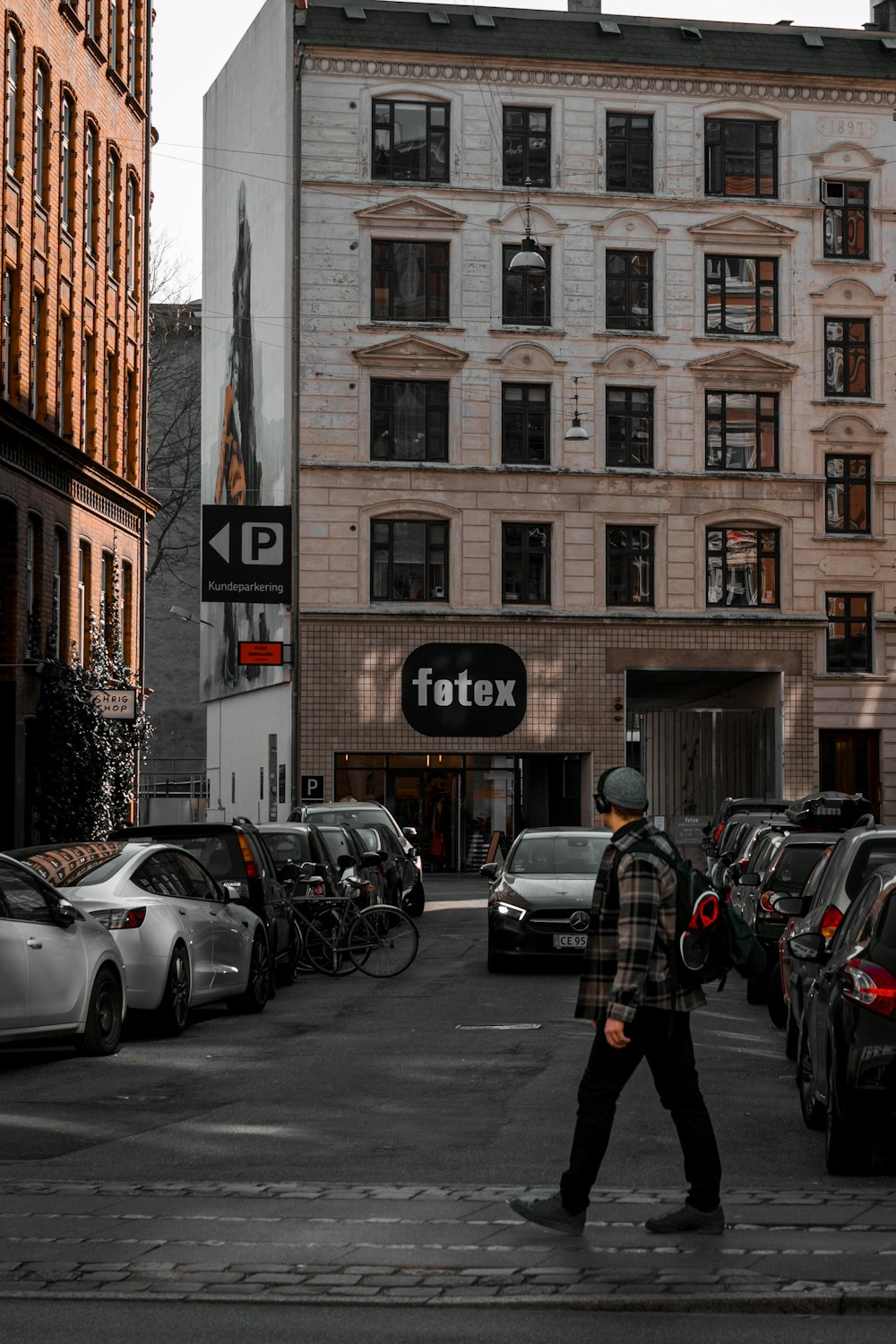 a man walking across a street next to tall buildings