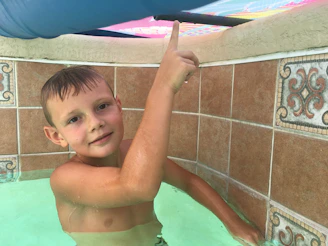A young child learning to swim with a supportive coach in a bright indoor pool.
