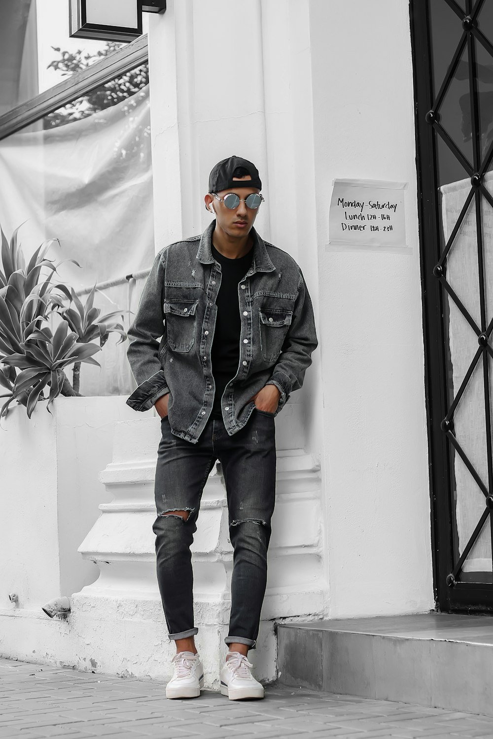 a man leaning against a wall wearing a denim jacket