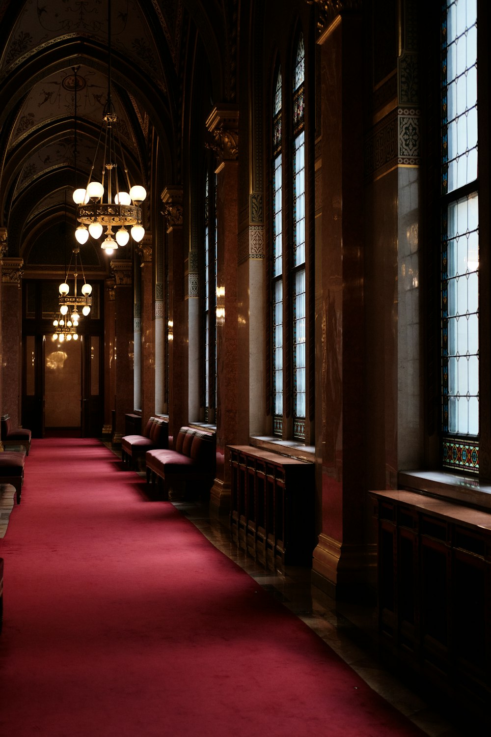 a red carpeted hallway with benches and windows