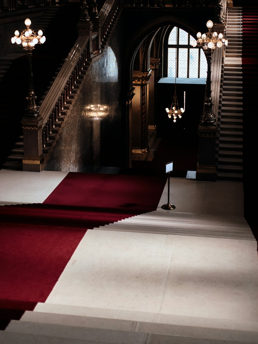 a red carpeted hall with a staircase and chandelier