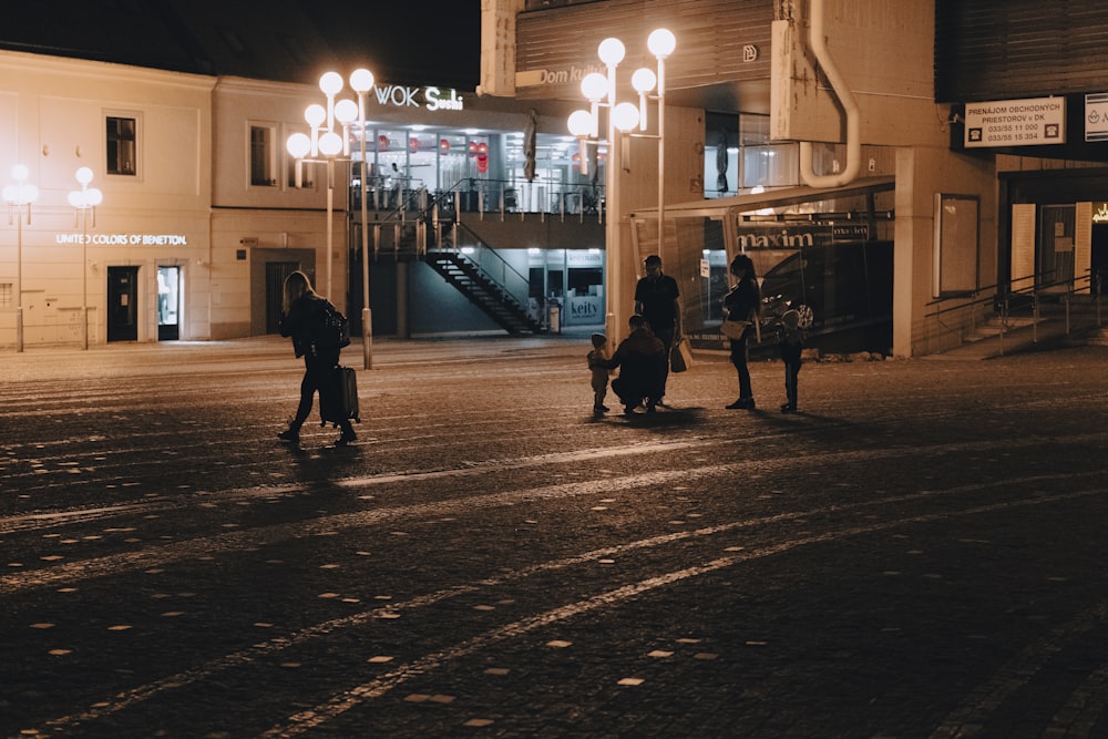 a group of people walking down a street at night