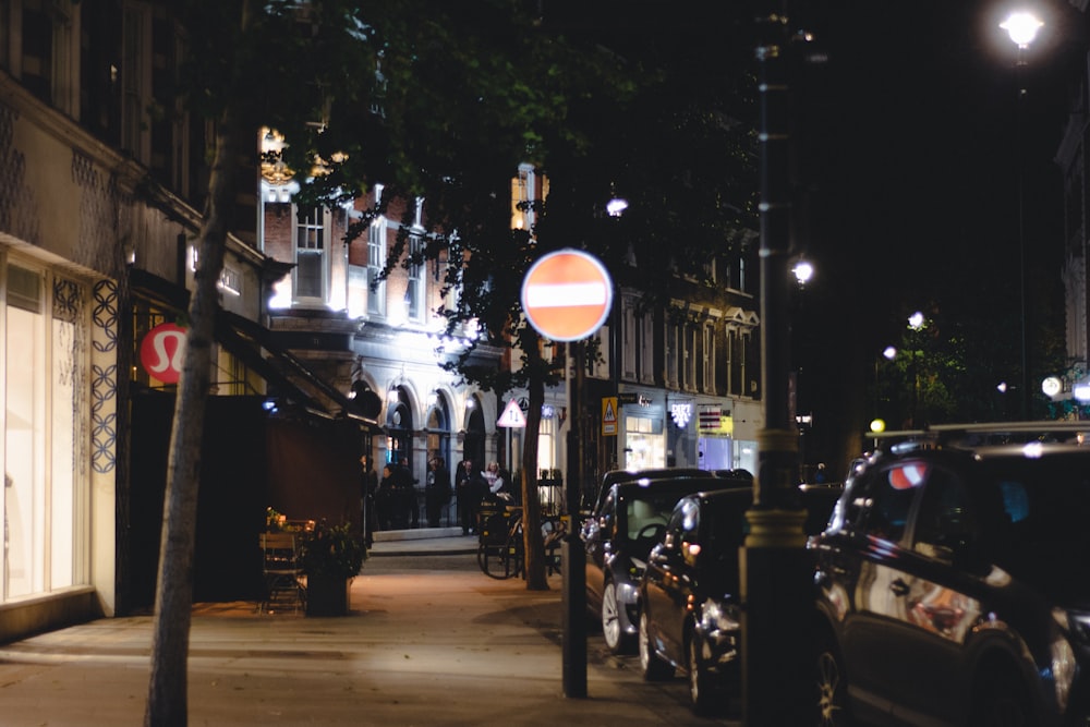 a city street at night with cars parked on the side of the street