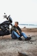 a man sitting on the ground next to a motorcycle