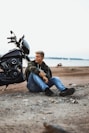 a man sitting on the ground next to a motorcycle