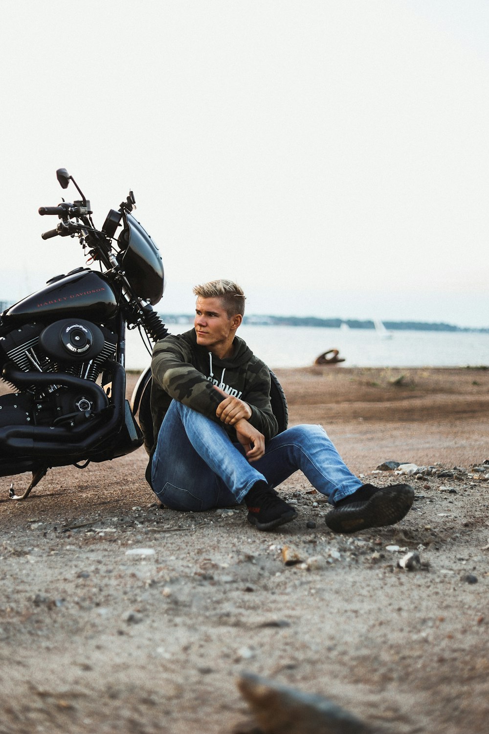 a man sitting on the ground next to a motorcycle
