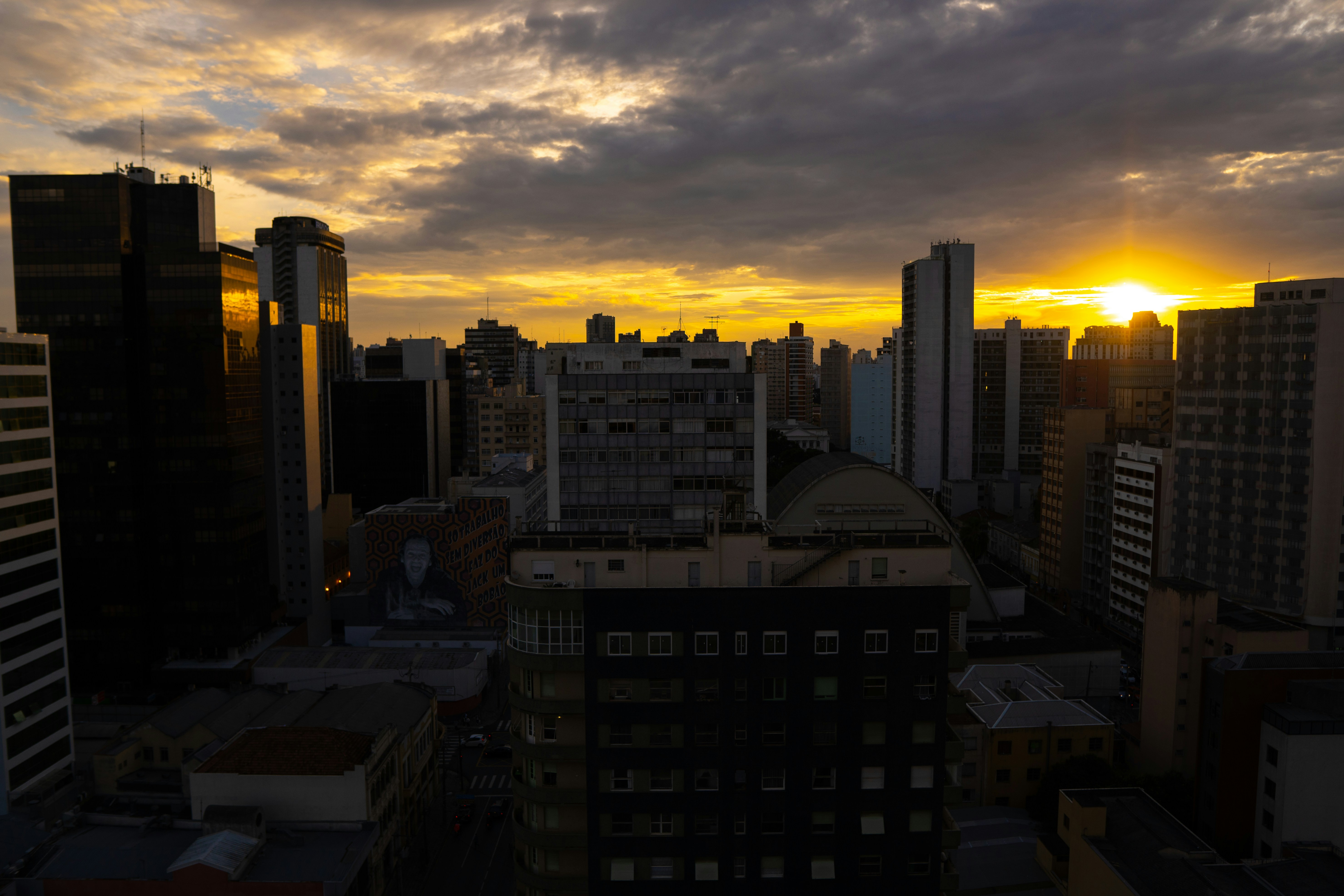 the sun is setting over a city with tall buildings