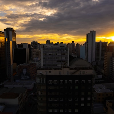 the sun is setting over a city with tall buildings