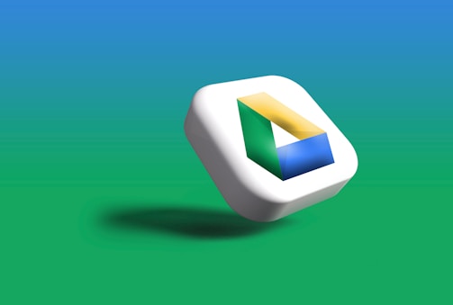 A three-dimensional icon featuring the Google Drive logo, resting against a gradient background that transitions from blue at the top to green at the bottom. The logo consists of a triangle formed by three colored sections: green, yellow, and blue.