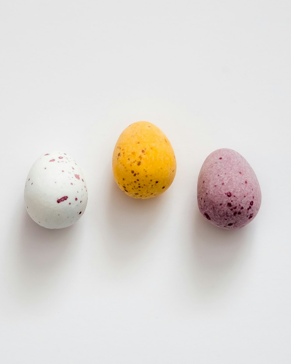 서로 옆에 앉아있는 세 개의 다른 색깔의 달걀