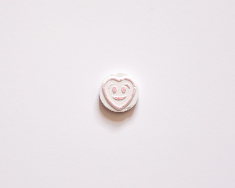 un bouton blanc avec un smiley dessus