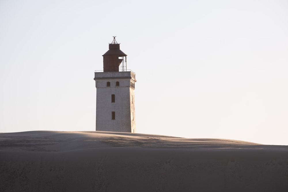 un phare assis au sommet d’une colline de sable