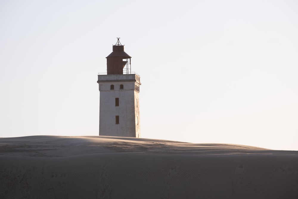 a light house sitting on top of a sandy hill