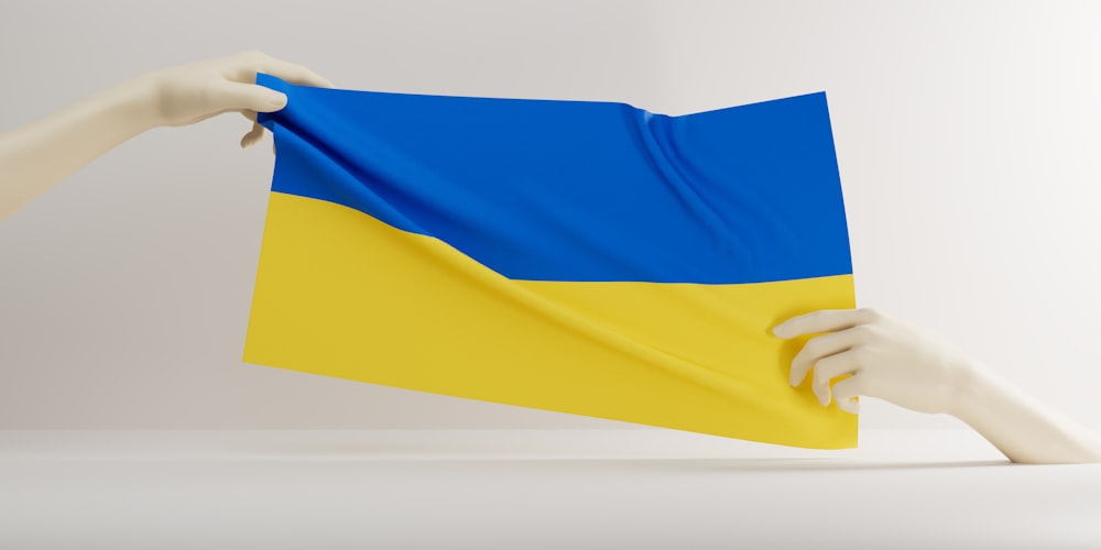 a hand holding a blue and yellow flag