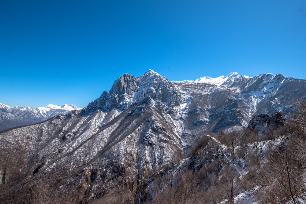 a mountain range covered in snow under a blue sky