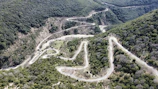 A winding mountain path carved through lush green hills in Himachal Pradesh.