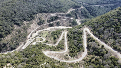 A winding mountain path carved through lush green hills in Himachal Pradesh.