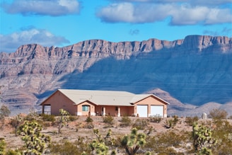 a house in the middle of a desert with mountains in the background