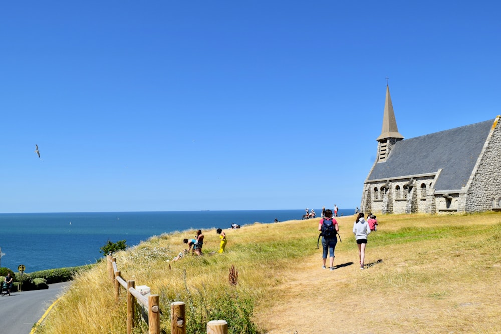 a group of people walking up a hill next to a church