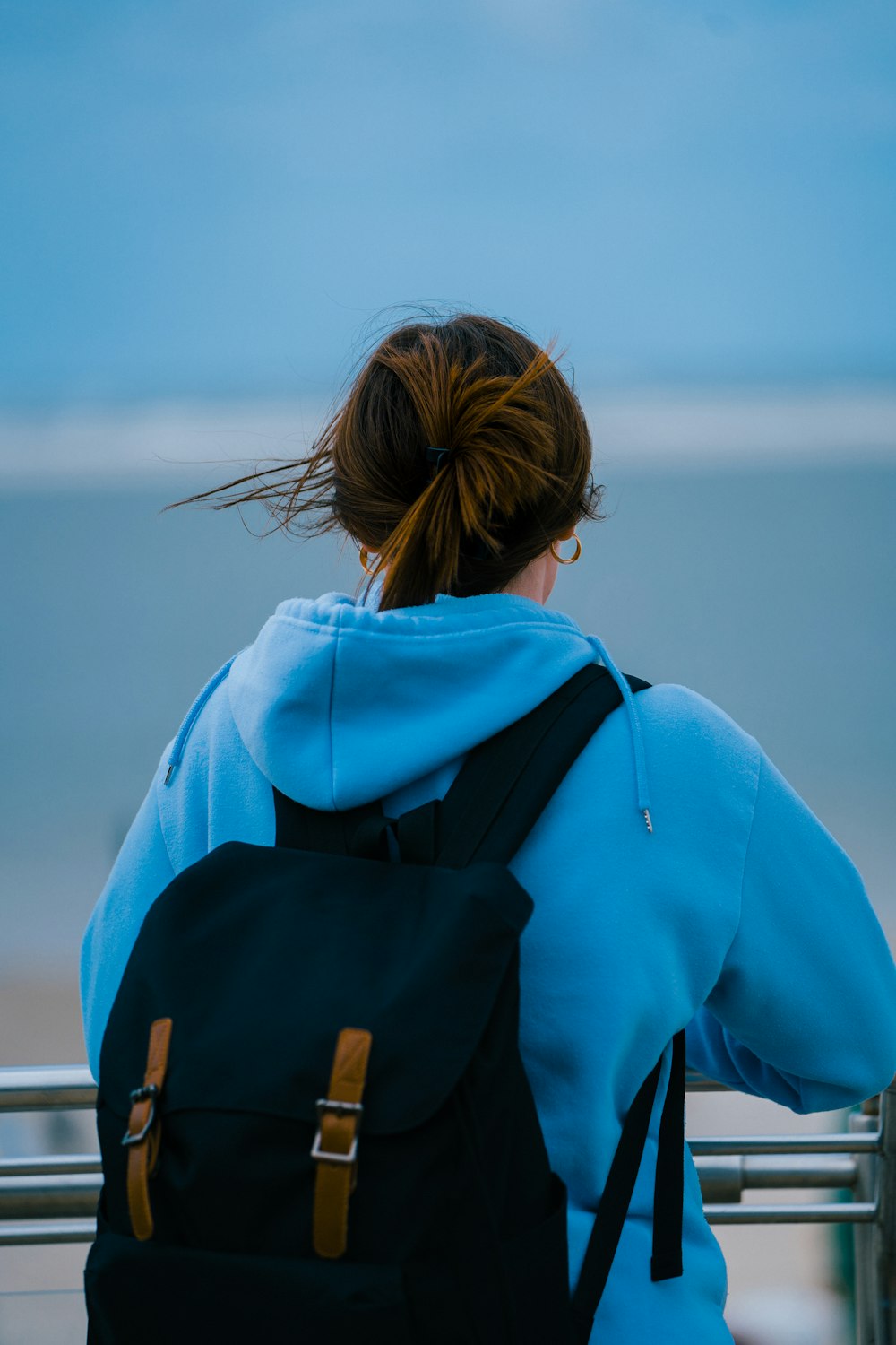 a woman sitting on a bench looking at the ocean