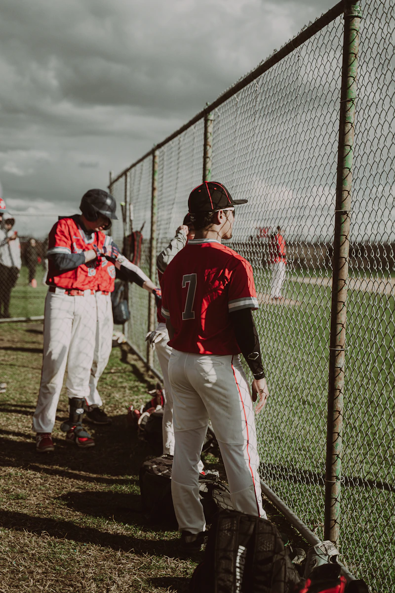 Baseball player holding a bat by the fence